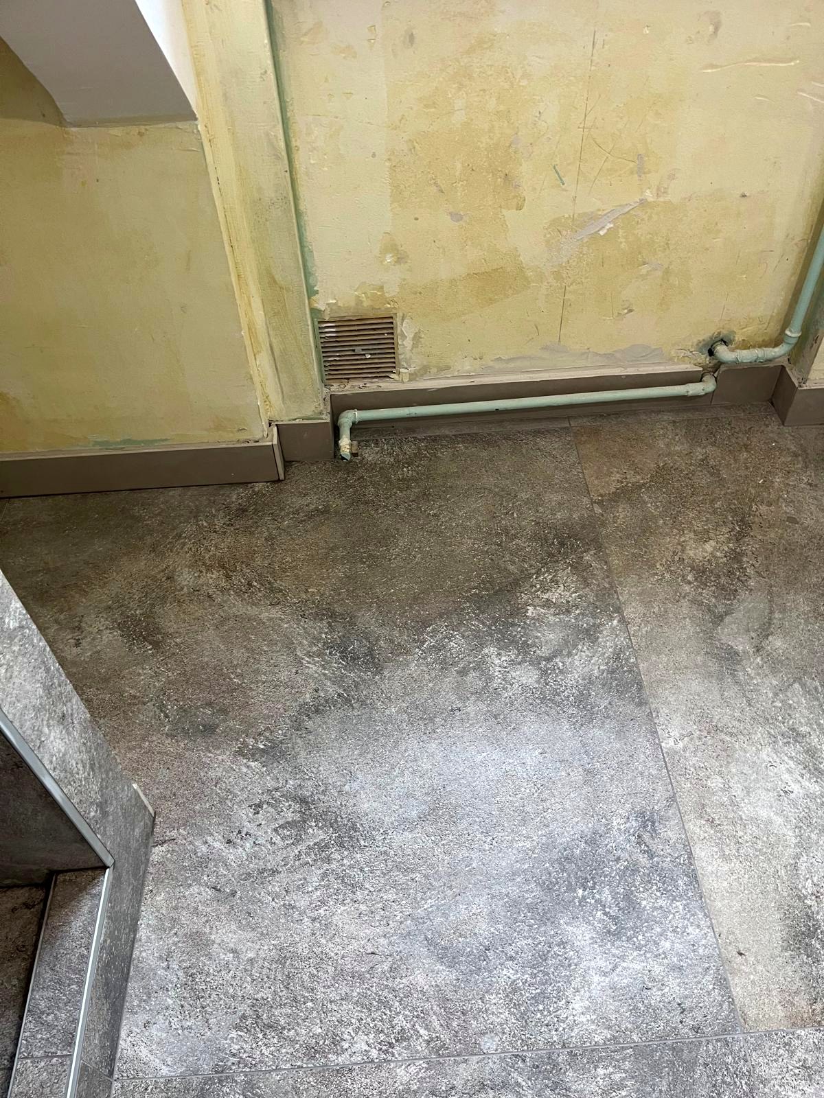 Détail de murs dégarnis, de canalisations apparentes et d'un sol de chantier — CAREN