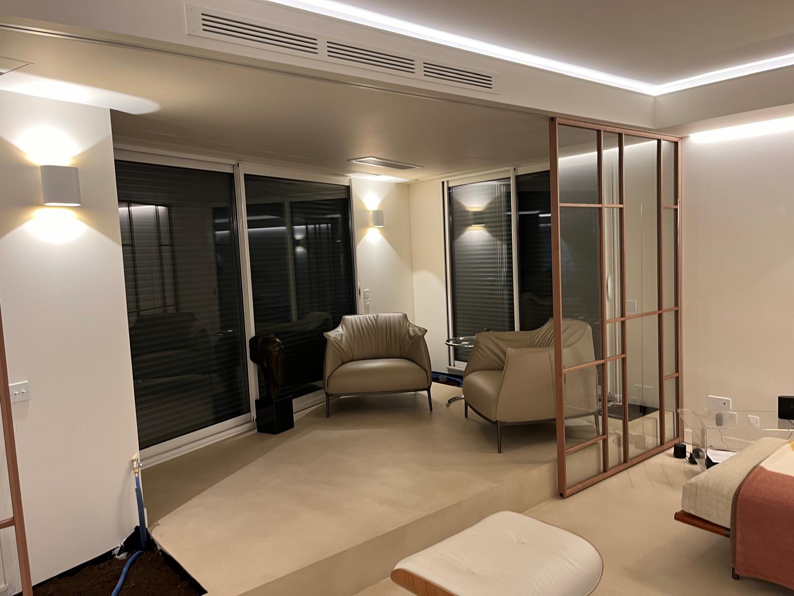 Espace salon avec fauteuils et séparation vitrée à montants bois — chantier CAREN