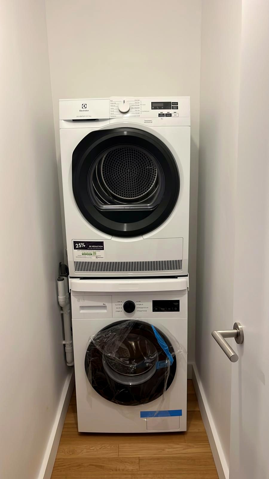 Lave-linge et sèche-linge superposés dans une niche aux murs blancs — chantier CAREN